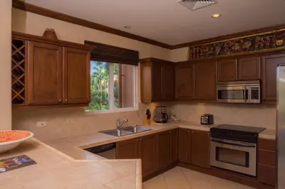 a kitchen with wooden cabinets and a sink at Bay Residence 7C 3 bdr Ocean View in Los Suenos in Herradura
