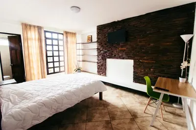 a bedroom with a bed and a brick wall at HOTEL TERRAZAS BOUTIQUE in Los Yoses