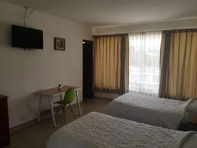 a hotel room with two beds and a desk and a television at HOTEL TERRAZAS BOUTIQUE in Los Yoses