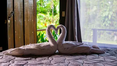 two pink swans sitting on top of a bed at La Fortuna Waterfall Bungalows in Fortuna