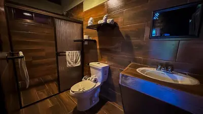 a bathroom with a toilet and a sink at La Fortuna Waterfall Bungalows in Fortuna