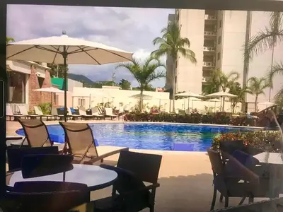 a swimming pool with chairs and tables and an umbrella at Jaco Oceanfront Condo #1119 in a Luxury Resort in Jacó