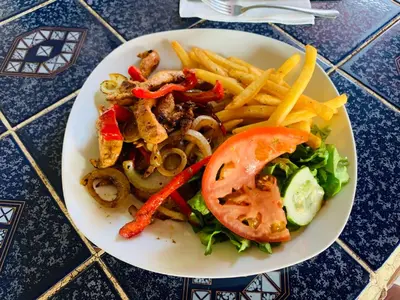 a plate of food with a sandwich and french fries at HOTEL Cabinas JACOMAR in Jacó