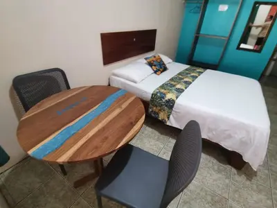a bedroom with a bed and a table and chairs at HOTEL Cabinas JACOMAR in Jacó