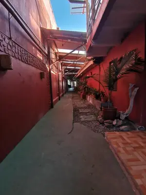 an empty hallway of a red building with plants at HOTEL Cabinas JACOMAR in Jacó