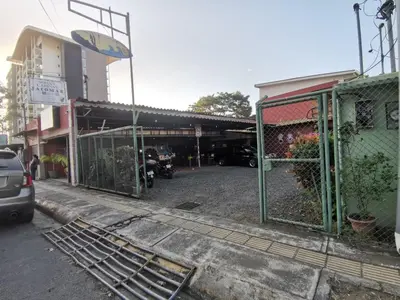 a parking lot with a gate in front of a building at HOTEL Cabinas JACOMAR in Jacó