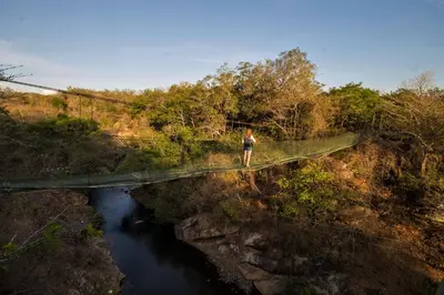 a person walking across a bridge over a river at Cañon de la Vieja Lodge in Liberia
