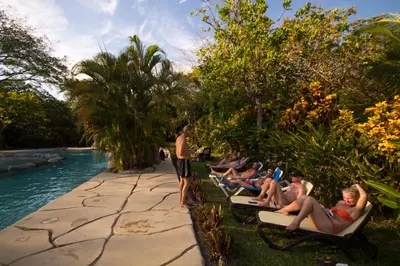 a group of people sitting on lounge chairs by a pool at Cañon de la Vieja Lodge in Liberia