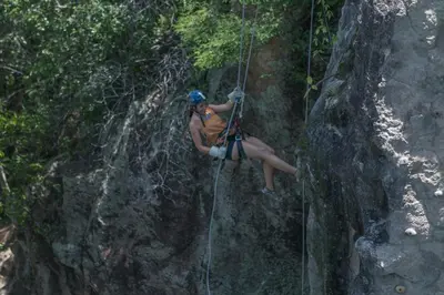 a woman on a rock climbing in the jungle at Cañon de la Vieja Lodge in Liberia