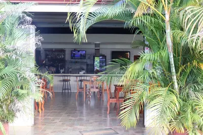 a restaurant with a bar with chairs and palm trees at Cabinas Sueño Real in San Rafael