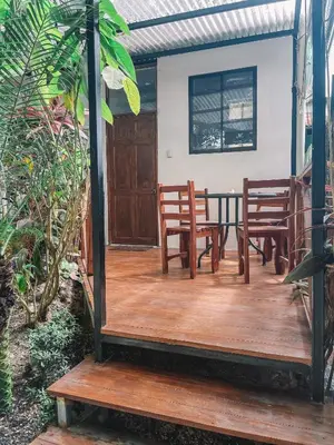 a wooden deck with two chairs and a table at El Gato Rojas Surf Hostel in Santa Teresa Beach