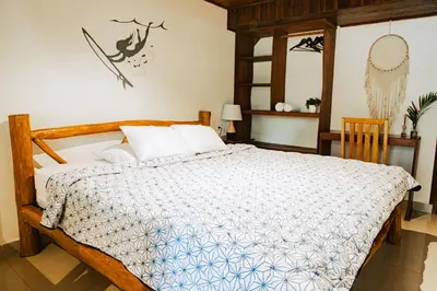 a bedroom with a large bed with a wooden frame at El Gato Rojas Surf Hostel in Santa Teresa Beach