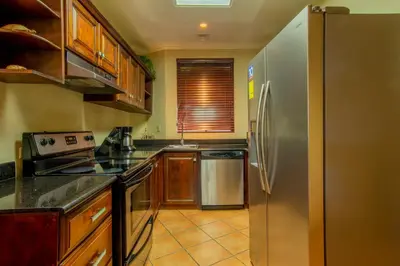 a kitchen with a stainless steel refrigerator and wooden cabinets at Tropical 2BR Condo with Partial Ocean View - Bougainvillea - Reserva Conchal in Playa Conchal