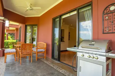 a patio with a stove and a table with chairs at Tropical 2BR Condo with Partial Ocean View - Bougainvillea - Reserva Conchal in Playa Conchal