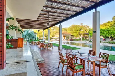 an outdoor patio with tables and chairs and a pool at Tropical 2BR Condo with Partial Ocean View - Bougainvillea - Reserva Conchal in Playa Conchal