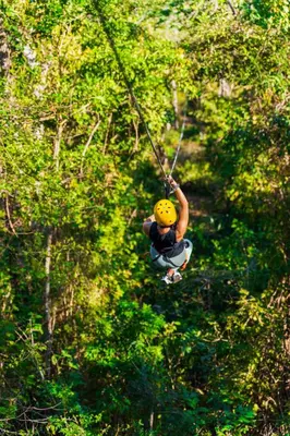a person in a yellow helmet hanging from a rope at Tropical 2BR Condo with Partial Ocean View - Bougainvillea - Reserva Conchal in Playa Conchal
