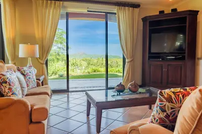 a living room with a tv and a couch and a table at Tropical 2BR Condo with Partial Ocean View - Bougainvillea - Reserva Conchal in Playa Conchal