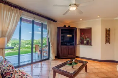 a living room with a couch and a table at Tropical 2BR Condo with Partial Ocean View - Bougainvillea - Reserva Conchal in Playa Conchal