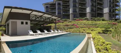 a swimming pool with chairs and a building at Adults Only 1BR Condo - Roble Sabana - Reserva Conchal Golf Resort in Playa Conchal