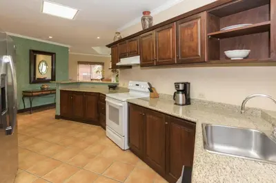 a kitchen with wooden cabinets and white appliances at Luxury 3BR Condo with Partial Ocean View - Bougainvillea - Reserva Conchal in Playa Conchal