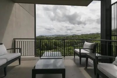 a balcony with chairs and a table and a view at Cozy 1BR Condo with Partial Ocean View - Roble Sabana - Reserva Conchall in Playa Conchal