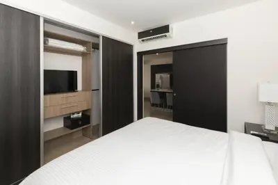a bedroom with a bed and a flat screen tv at Cozy 1BR Condo with Partial Ocean View - Roble Sabana - Reserva Conchall in Playa Conchal