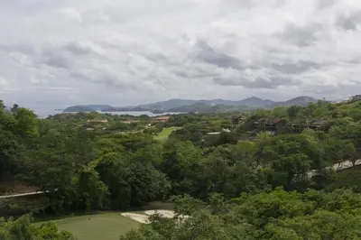 a view of a golf course with mountains in the background at Cozy 1BR Condo with Partial Ocean View - Roble Sabana - Reserva Conchall in Playa Conchal
