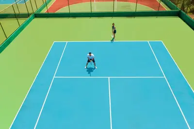 two people are standing on a tennis court at Cozy 1BR Condo with Partial Ocean View - Roble Sabana - Reserva Conchall in Playa Conchal
