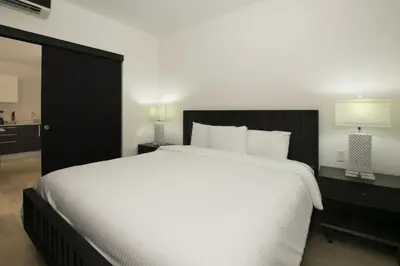 a bedroom with a large white bed with a black headboard at Cozy 1BR Condo with Partial Ocean View - Roble Sabana - Reserva Conchall in Playa Conchal