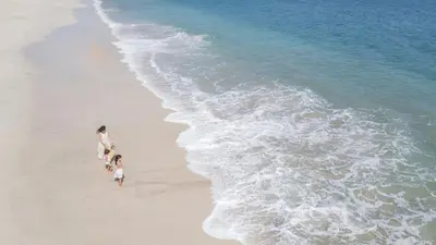 a woman and two children walking on the beach at Incredible Ocean-View Penthouse - Jobo - Reserva Conchal Golf Resort in Playa Conchal