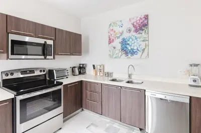 a kitchen with wooden cabinets and a white counter top at Apt AC WIFI Mountain View Near beach Costa Rica in Jacó