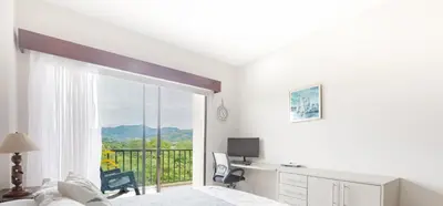 a bedroom with a bed and a desk and a window at Apt AC WIFI Mountain View Near beach Costa Rica in Jacó