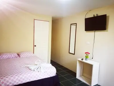 a bedroom with a bed and a tv on the wall at Habitación Privada - Apartamentos Morpho CR in Quepos