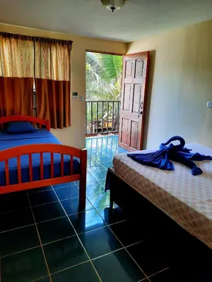 a bedroom with two beds and a door to a balcony at Habitación Privada - Apartamentos Morpho CR in Quepos
