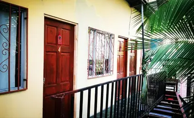 a house with a staircase and a wooden door at Habitación Privada - Apartamentos Morpho CR in Quepos