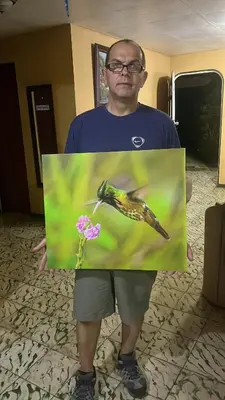 a man holding a picture of a bird and a flower at Cabañas Colibrí Tayutic in Turrialba