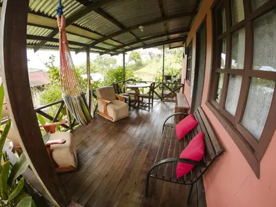 a porch with a hammock and a table and chairs at Cabañas Colibrí Tayutic in Turrialba