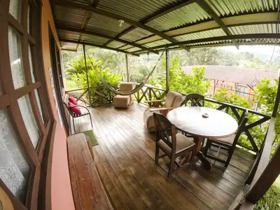 a porch with a table and chairs on a balcony at Cabañas Colibrí Tayutic in Turrialba