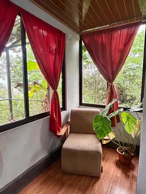 a living room with a chair and windows at Cabañas Colibrí Tayutic in Turrialba