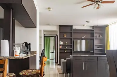 a kitchen with black cabinets and a ceiling fan at Lujoso condominio con lavadora y secadora, S. José in San José