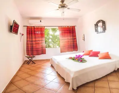 a bedroom with a large white bed with red curtains at Hotel Laguna del Cocodrilo in Tamarindo
