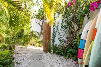 a path through a garden with surfboards and flowers at Lucero in Santa Teresa Beach