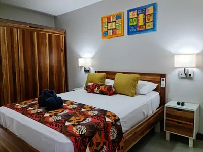 a bedroom with a large bed with a wooden headboard at Ballena Paradise Apartahotel in Uvita