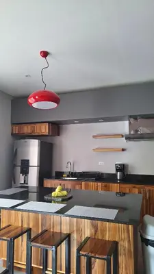 a kitchen with a counter with stools and a red light at Ballena Paradise Apartahotel in Uvita