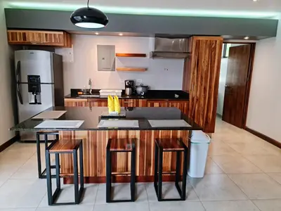 a kitchen with a counter with stools and a refrigerator at Ballena Paradise Apartahotel in Uvita