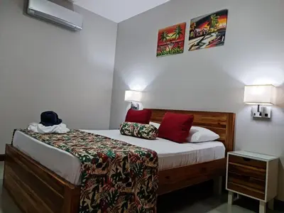 a small bedroom with a bed with red pillows at Ballena Paradise Apartahotel in Uvita