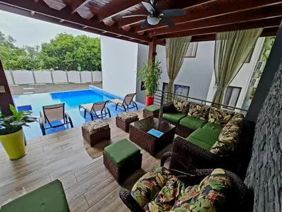 a living room with a couch and chairs and a pool at Ballena Paradise Apartahotel in Uvita