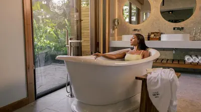 a woman sitting in a bath tub in a bathroom at Tabacón Thermal Resort & Spa in Fortuna