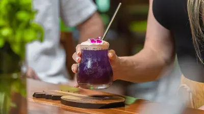 a woman holding a purple drink with a straw at Tabacón Thermal Resort & Spa in Fortuna