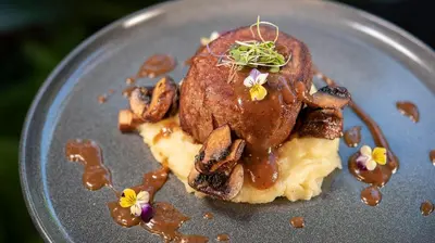 a plate of food with a piece of meat and mushrooms at Tabacón Thermal Resort & Spa in Fortuna